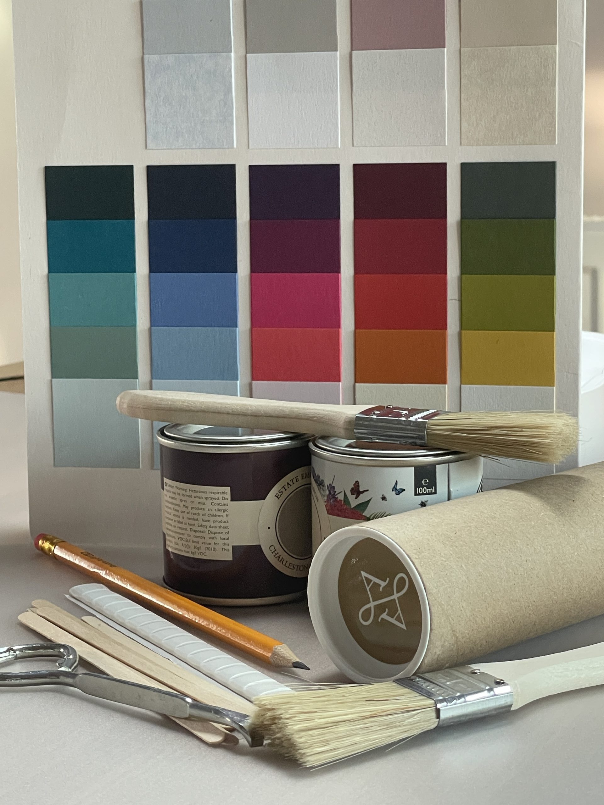 A kit for testing paint colours including lining paper, paintbrushes, stirrers, paint tin opener and pencil.